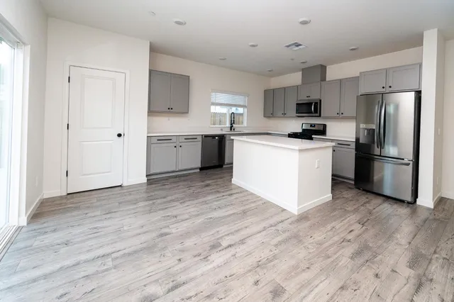 a kitchen with granite countertop a stove a sink and a refrigerator
