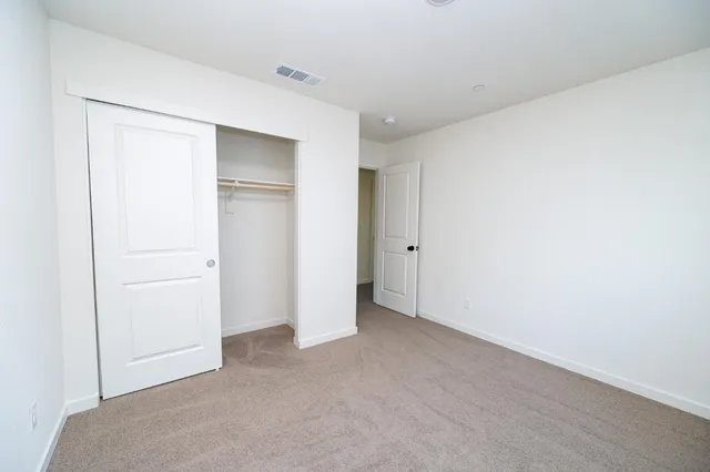 a view of an empty room with closet and a window