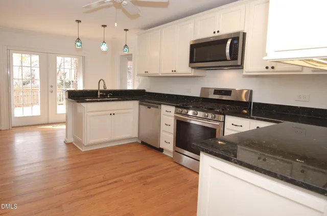 a kitchen with stainless steel appliances granite countertop a stove a sink and a microwave