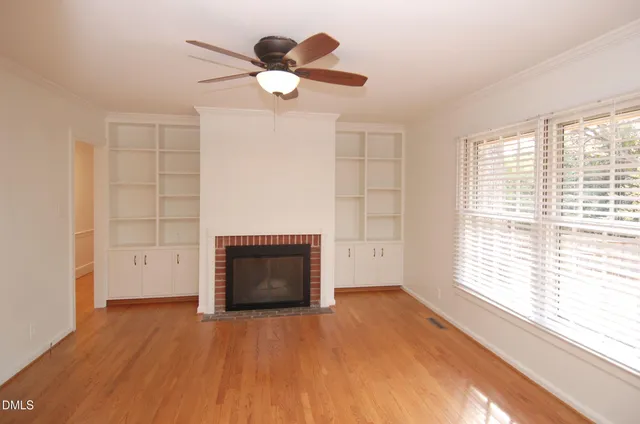 a view of empty room with wooden floor and fan