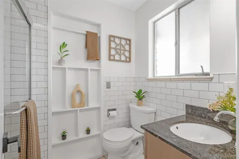 a bathroom with a granite countertop toilet sink and mirror
