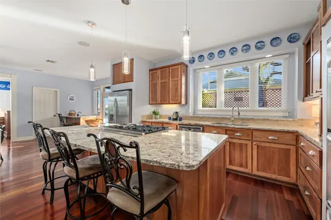 a kitchen with stainless steel appliances granite countertop a refrigerator a stove top oven and a dining table with wooden floor