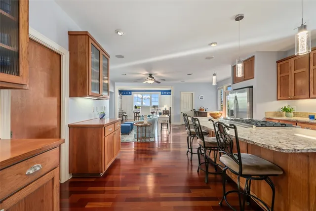 a kitchen with stainless steel appliances granite countertop a refrigerator a stove top oven and a dining table with wooden floor