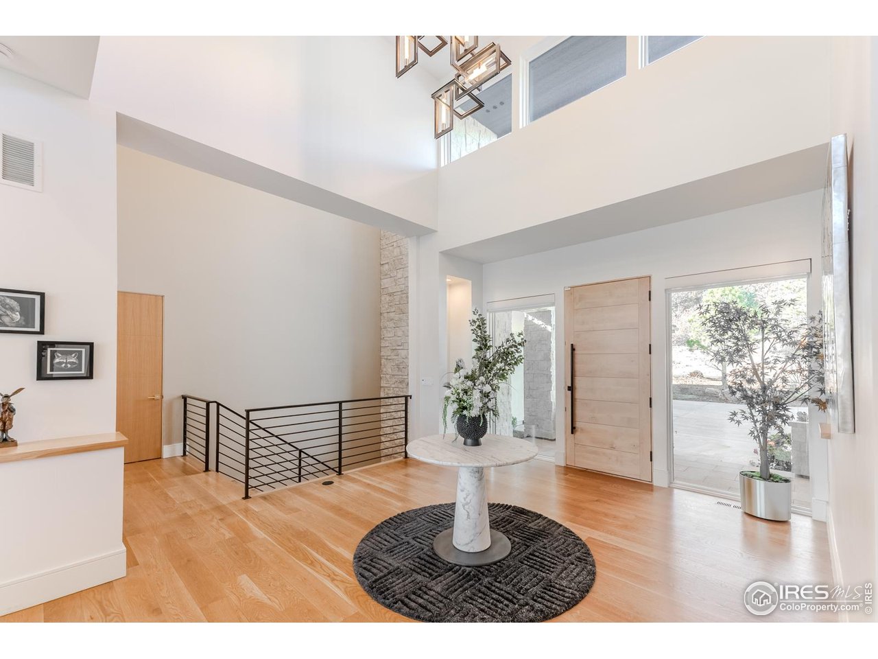 7572 Raphael Lane Littleton, CO 80125 - Photo 4 of 50 A grand two-story entry and modern door flanked by full-height glass invites light to pour across wide white-oak floors that extend uninterrupted throughout the main level.