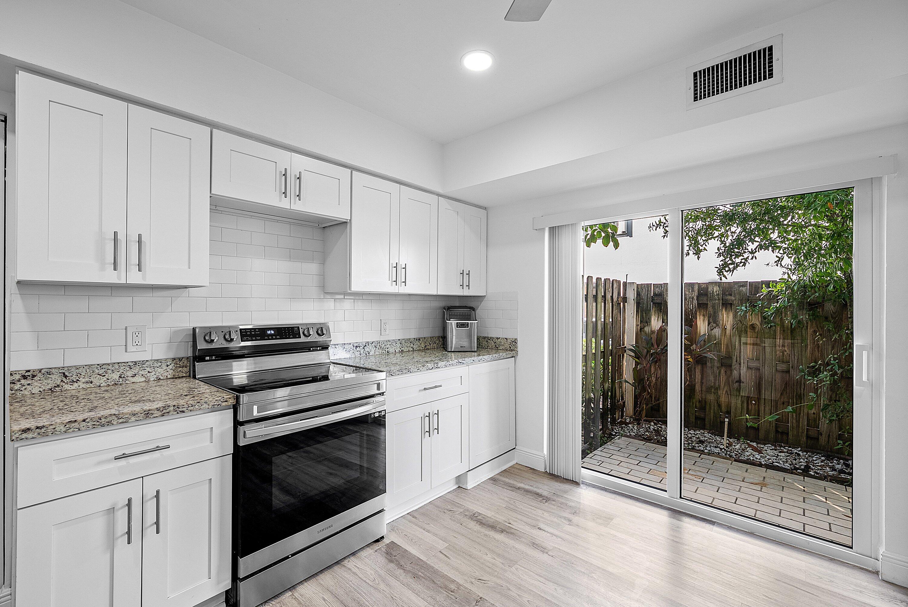 6165 Old Court Road, Unit 123 Boca Raton, FL 33433 - Photo 5 of 30 a kitchen with granite countertop a stove a sink and white cabinets