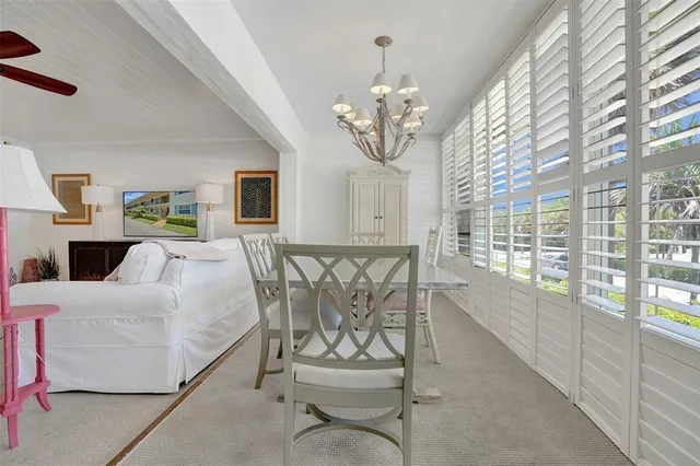 a view of a dining room with furniture a chandelier and large windows