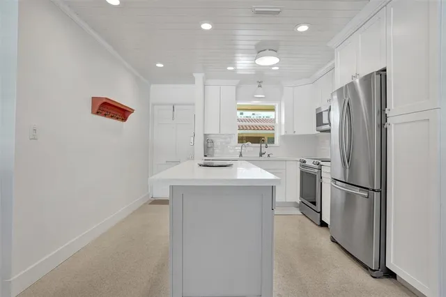 a kitchen with kitchen island a refrigerator sink and stove