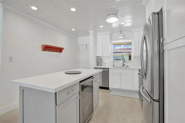 a kitchen with a sink a stove a refrigerator and white cabinets
