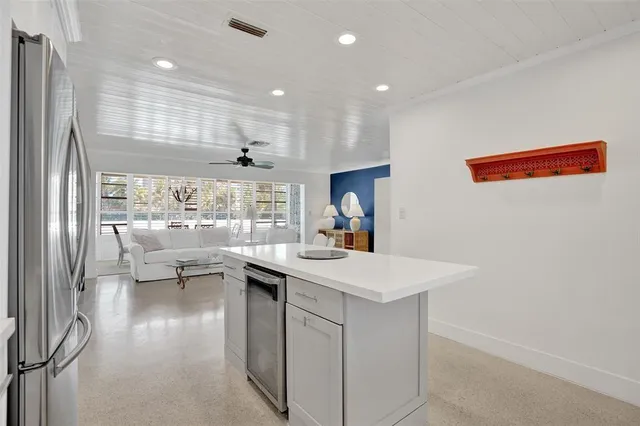 a kitchen with a sink and living room with stainless steel appliances