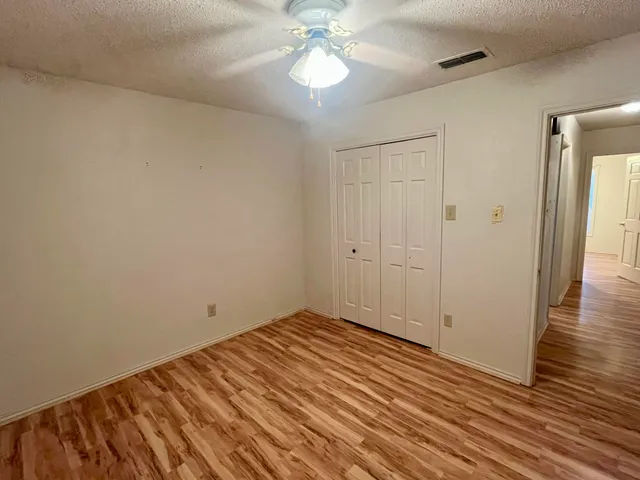 a view of a room with wooden floor and a ceiling fan