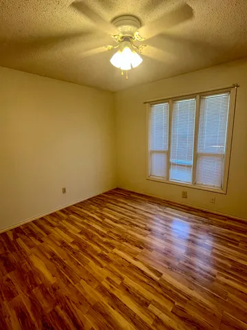 a view of empty room with wooden floor and fan