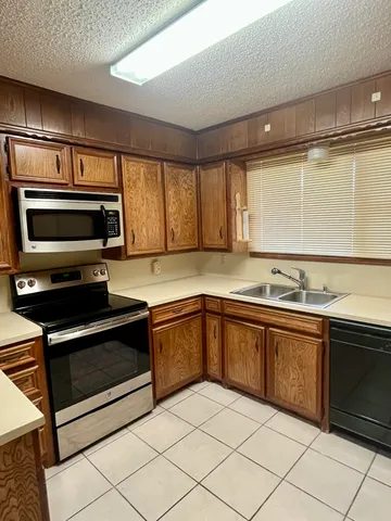 a kitchen with granite countertop a sink cabinets and stainless steel appliances