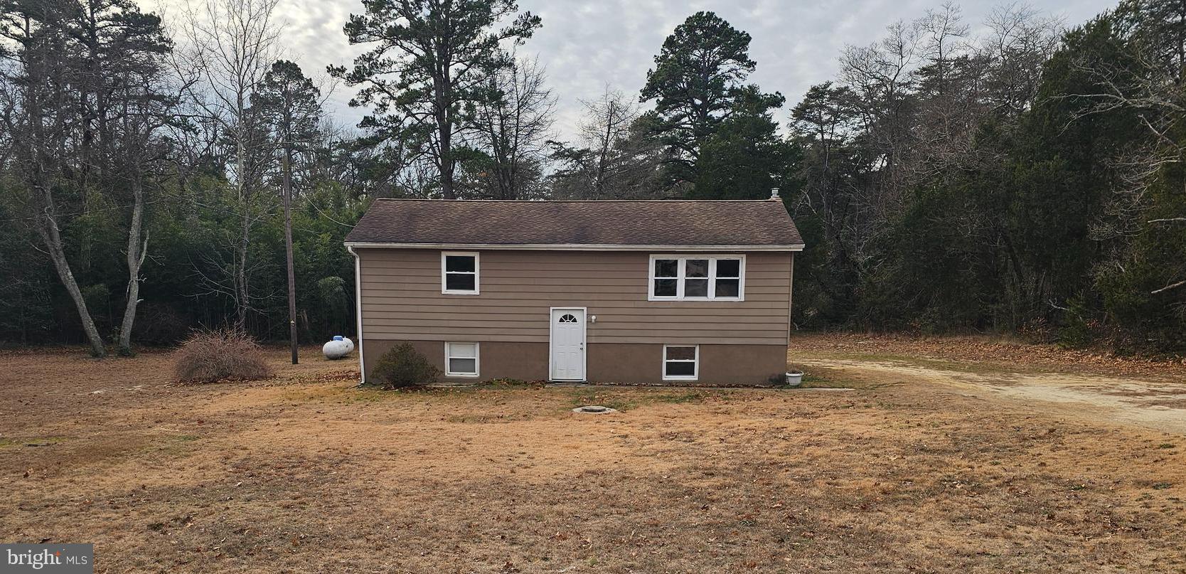 a front view of house with yard and trees in the background