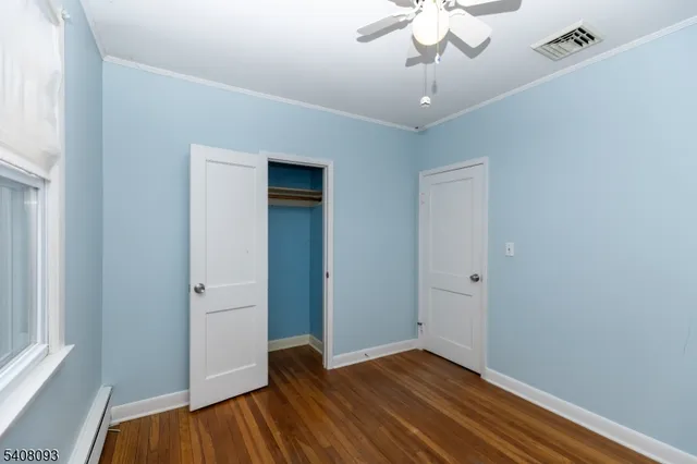 a view of empty room with wooden floor and fan