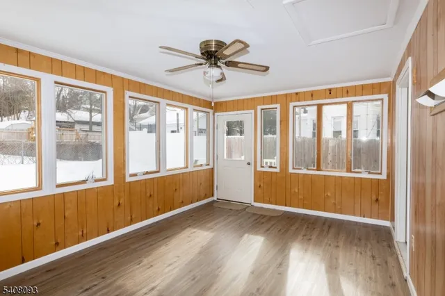 a view of empty room with wooden floor and fan