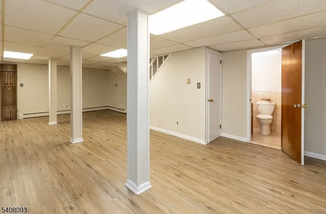 a view of a hallway with wooden floor and a bathroom