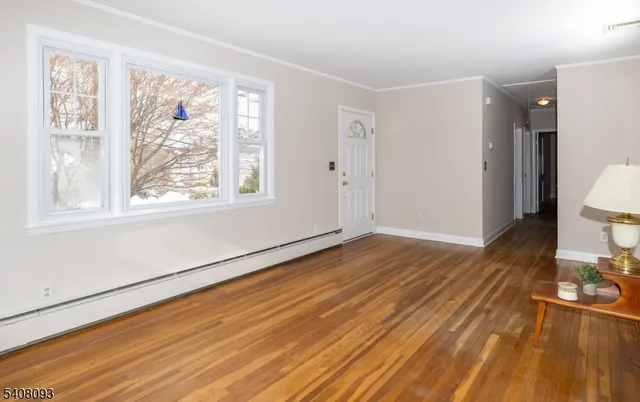 a view of an empty room with wooden floor and a window