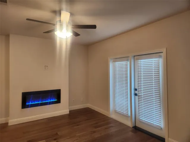 a view of an empty room with a window and wooden floor