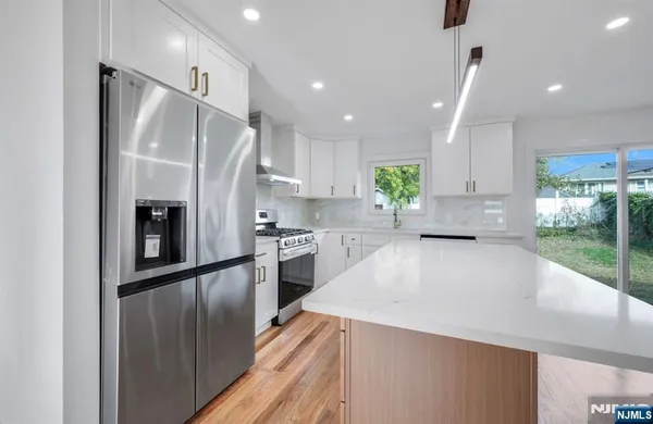 a large kitchen with stainless steel appliances a refrigerator and a wooden floor