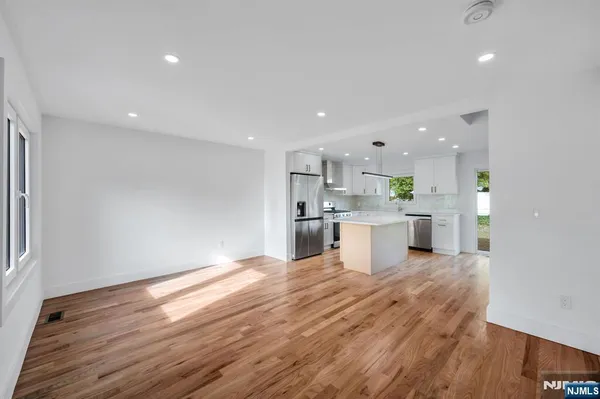 a open kitchen with kitchen island a sink dishwasher a stove and a refrigerator with wooden floor