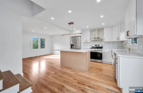 a large kitchen with kitchen island a sink wooden floor and a stove