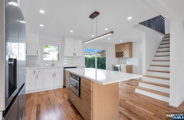 a large kitchen with kitchen island a stove a sink dishwasher and wooden floor