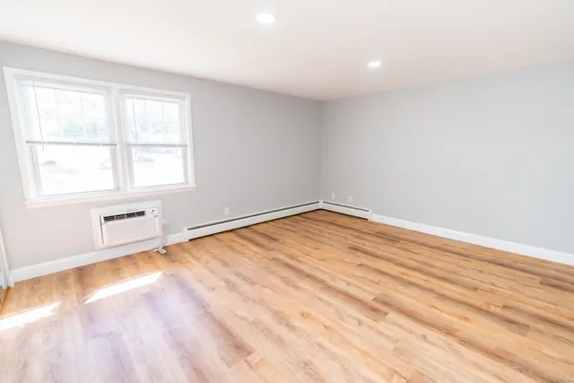 an empty room with wooden floor and windows
