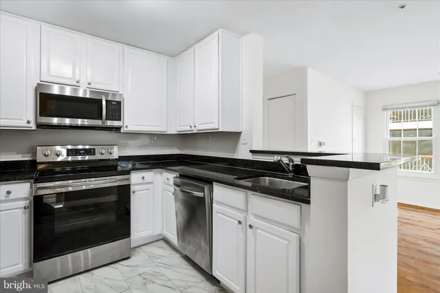 a kitchen with granite countertop white cabinets and stainless steel appliances