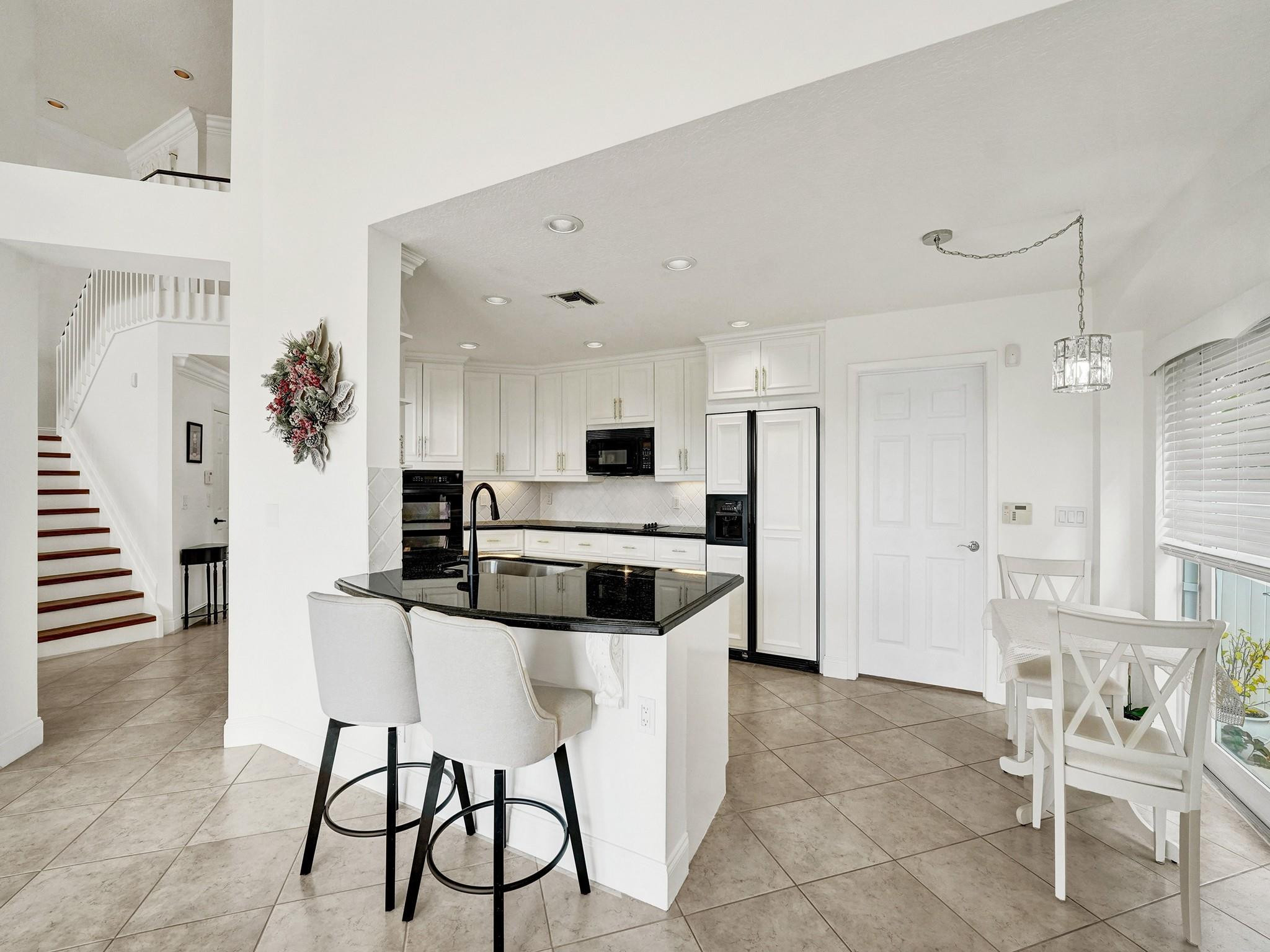 6298 Brava Way Boca Raton, FL 33433 - Photo 34 of 91 a kitchen with stainless steel appliances kitchen island granite countertop a table and chairs in it