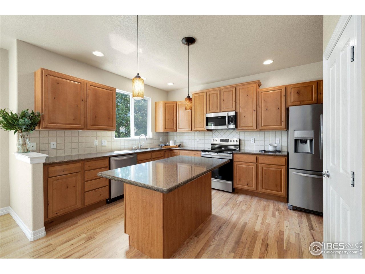 16836 Roberts Street Mead, CO 80542 - Photo 2 of 27 a kitchen with kitchen island granite countertop wooden floors stainless steel appliances a sink a counter top space and cabinets