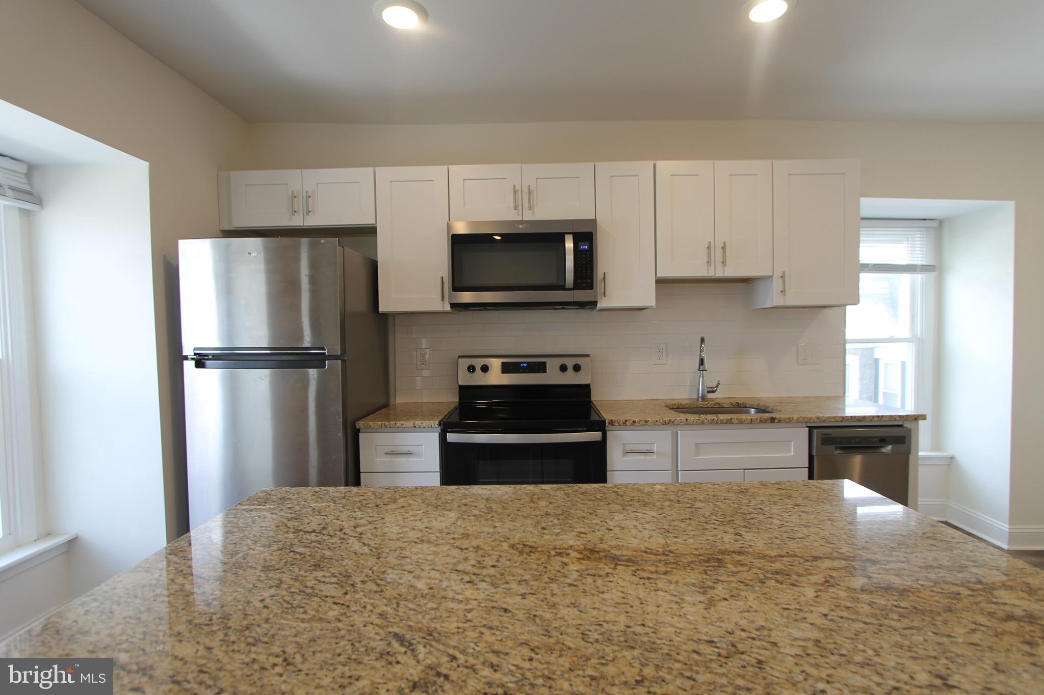204 High Street Philadelphia, PA 19144 - Photo 5 of 19 a kitchen with granite countertop a refrigerator stove and microwave