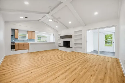 a big room with wooden floor and a kitchen