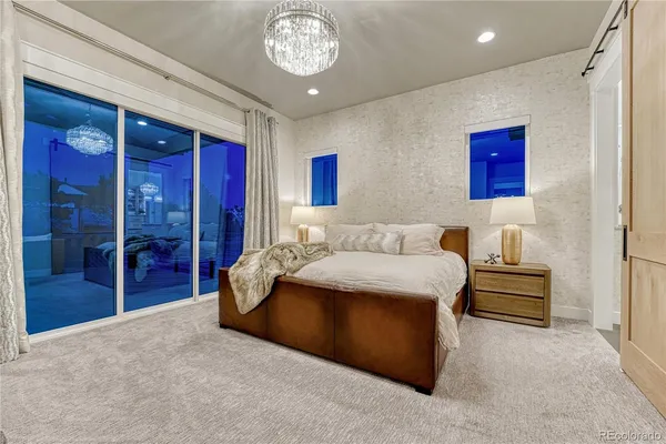 a large bed sitting in a bedroom next to a window and a chandelier