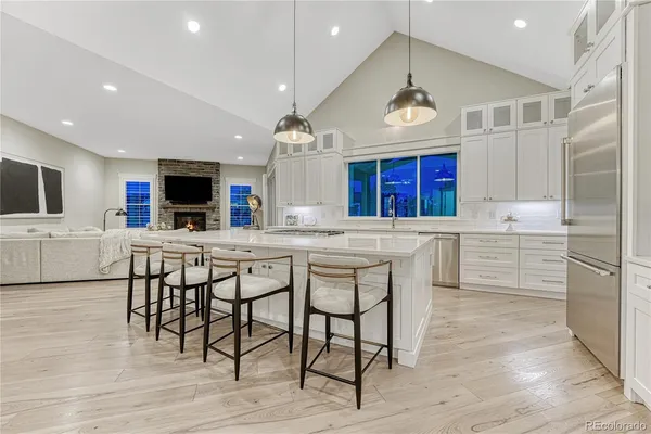 a kitchen with stainless steel appliances kitchen island granite countertop a table chairs sink and cabinets