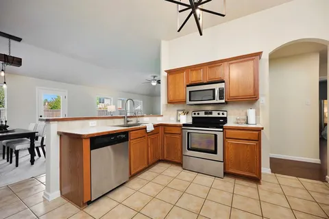 a kitchen with stainless steel appliances granite countertop a stove top oven a sink dishwasher and a refrigerator