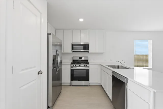 a kitchen with stainless steel appliances granite countertop a stove a sink and a refrigerator