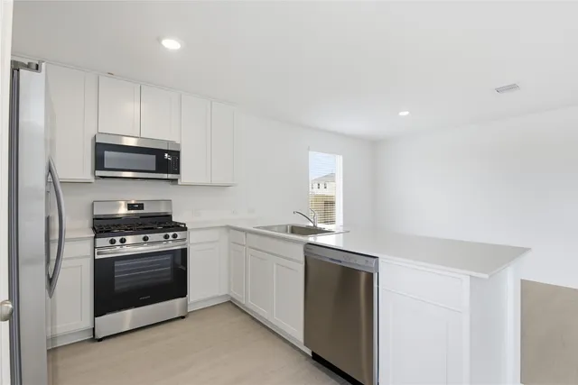 a kitchen with granite countertop white cabinets and stainless steel appliances