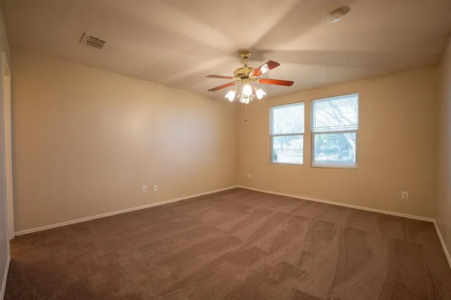 an empty room with windows and chandelier fan