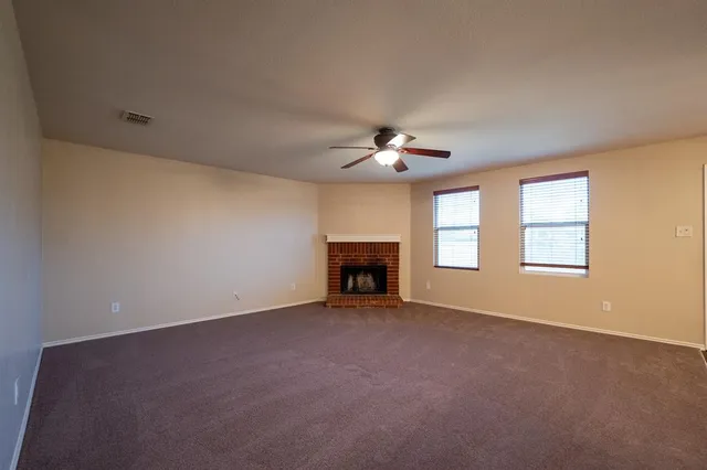 a view of an empty room with chandelier fan and fire place