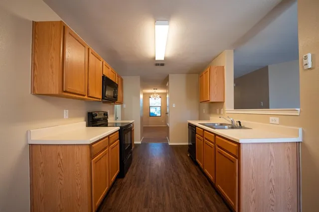 a kitchen with a sink stove top oven and wooden floor