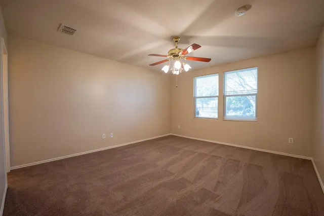 an empty room with windows and chandelier fan