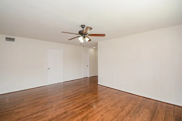 a view of a room with wooden floor and a ceiling fan