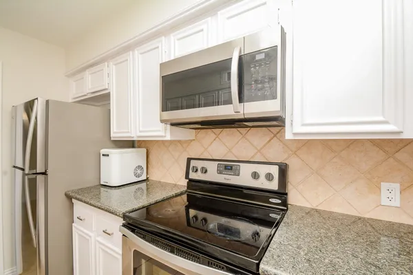 a kitchen with stainless steel appliances granite countertop a stove microwave and refrigerator