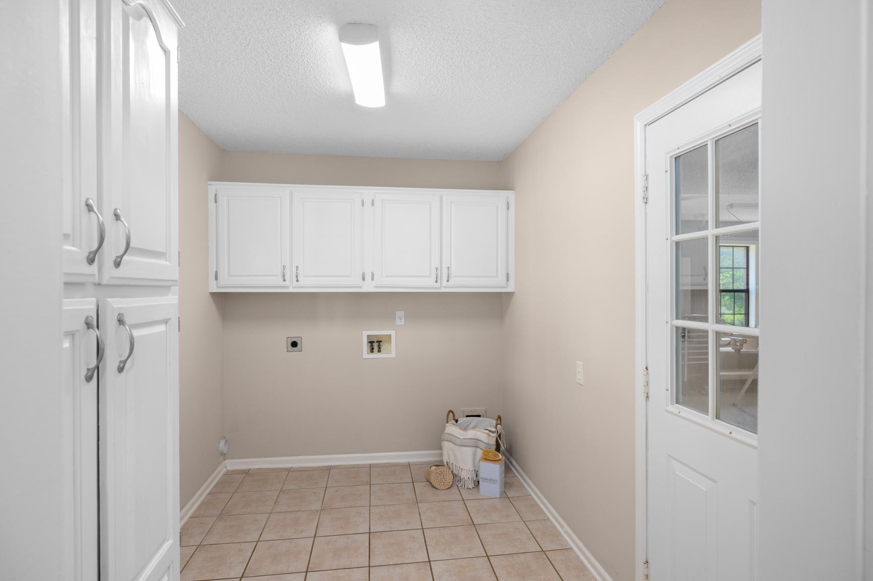 284 Pwr Loop Munford, TN 38058 - Photo 11 of 36 Laundry area featuring cabinet space, hookup for an electric dryer, hookup for a washing machine, a textured ceiling, and light tile patterned floors