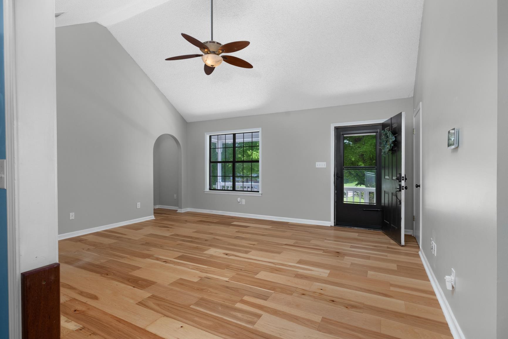 284 Pwr Loop Munford, TN 38058 - Photo 4 of 36 Unfurnished living room featuring arched walkways, light wood-style floors, ceiling fan, and lofted ceiling