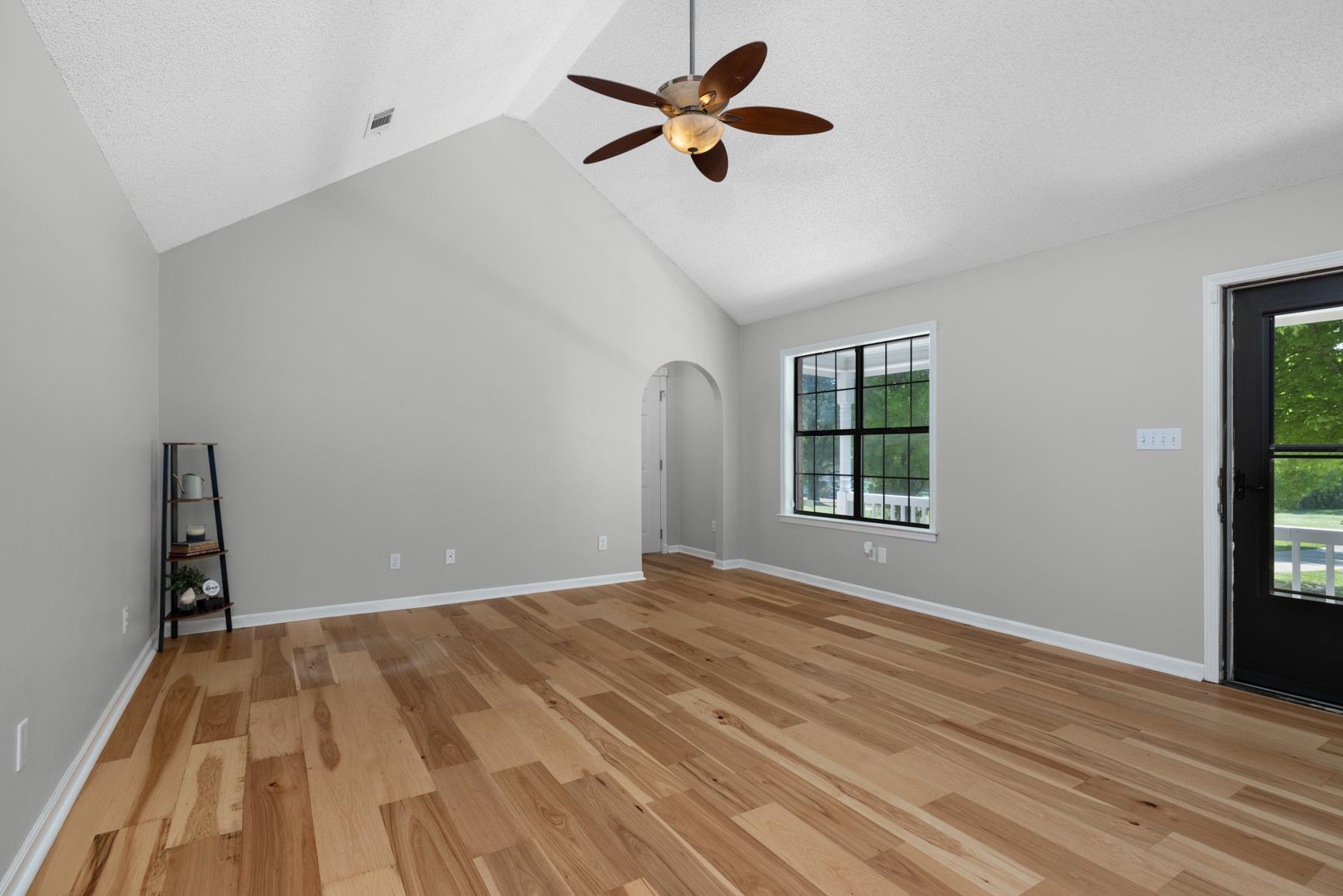 284 Pwr Loop Munford, TN 38058 - Photo 5 of 36 Unfurnished living room with arched walkways, light wood-type flooring, a ceiling fan, and a high textured ceiling