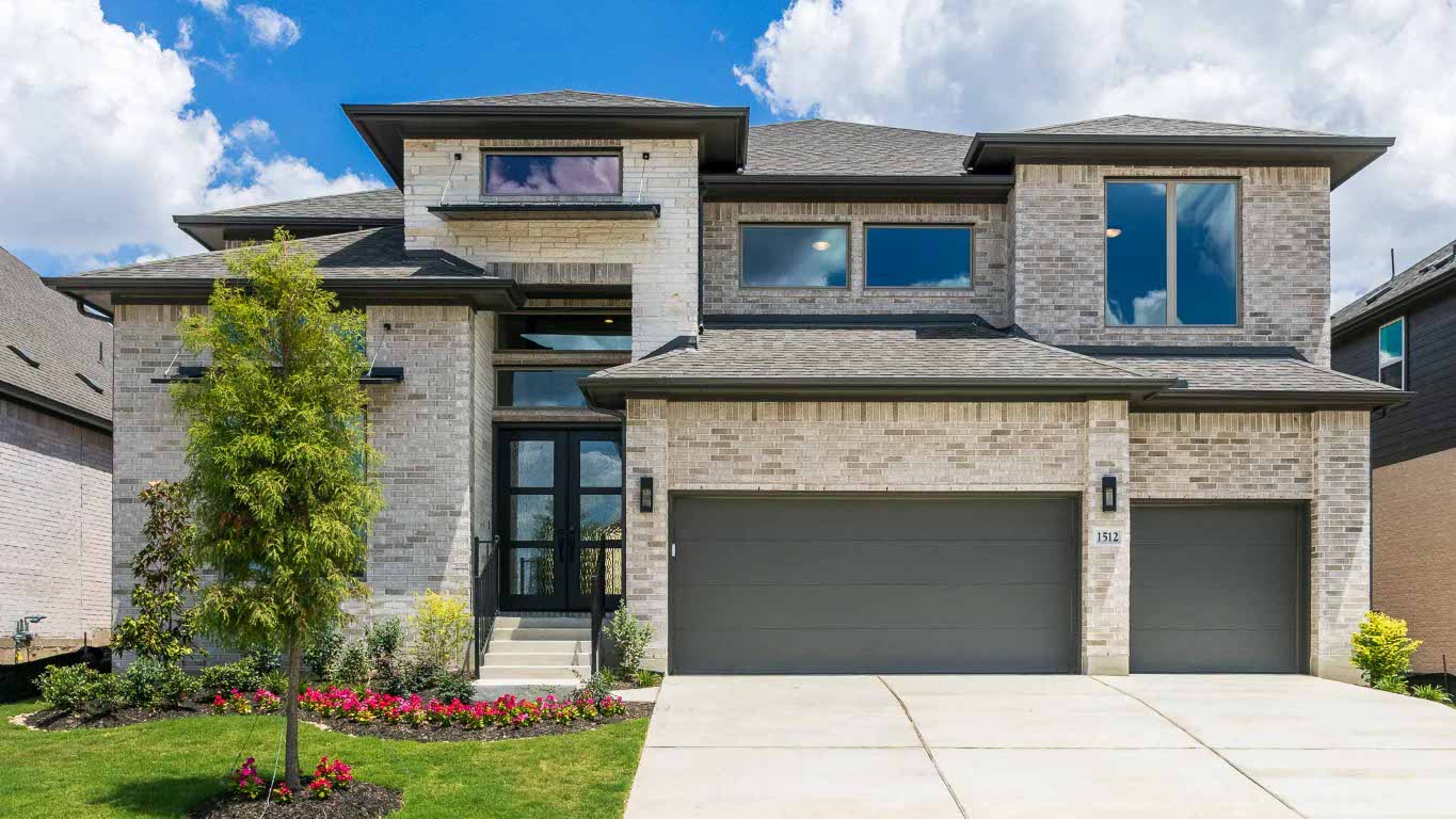 View of front of house featuring an attached garage, brick siding, driveway, and a shingled roof