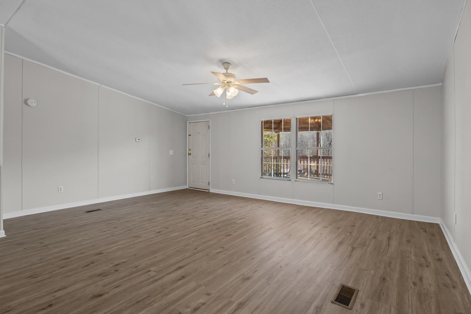 624 Nickletown Road Sugar Tree, TN 38380 - Photo 9 of 45 an empty room with wooden floor chandelier fan and windows