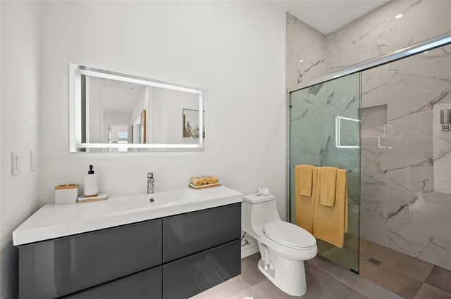 a bathroom with a sink mirror toilet and next to a window