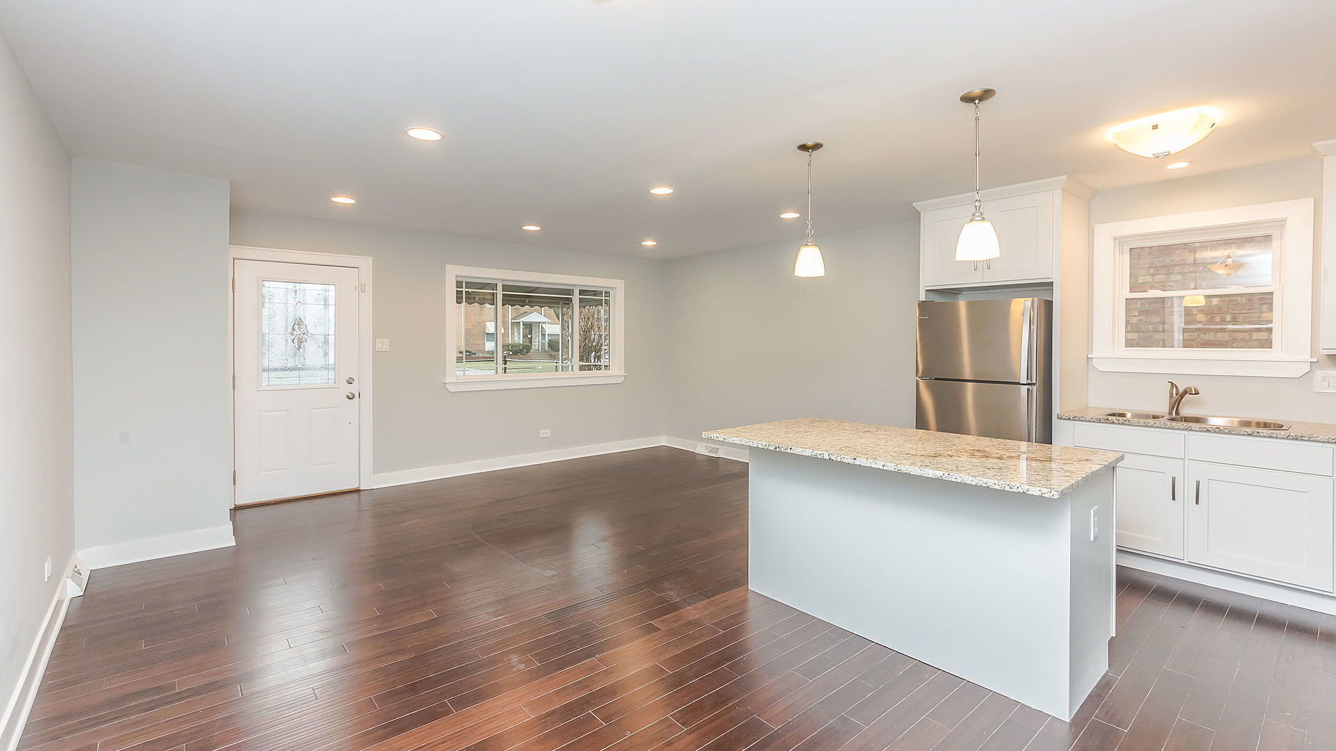 1159 West 112th Street Chicago, IL 60643 - Photo 2 of 27 a kitchen with granite countertop a stove a sink a refrigerator and white cabinets with wooden floor